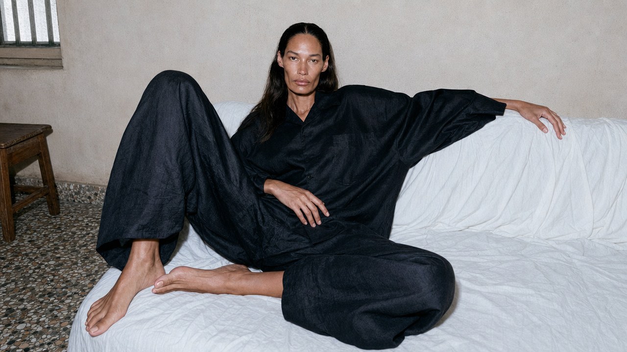 Model reclining on a white sofa in a black linen set